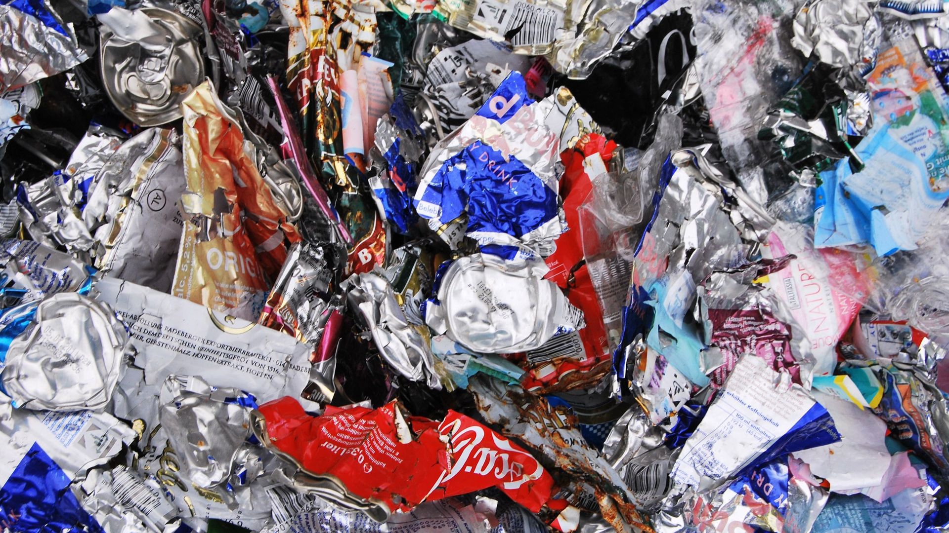 Crumpled and crushed aluminum cans and packaging in various colors