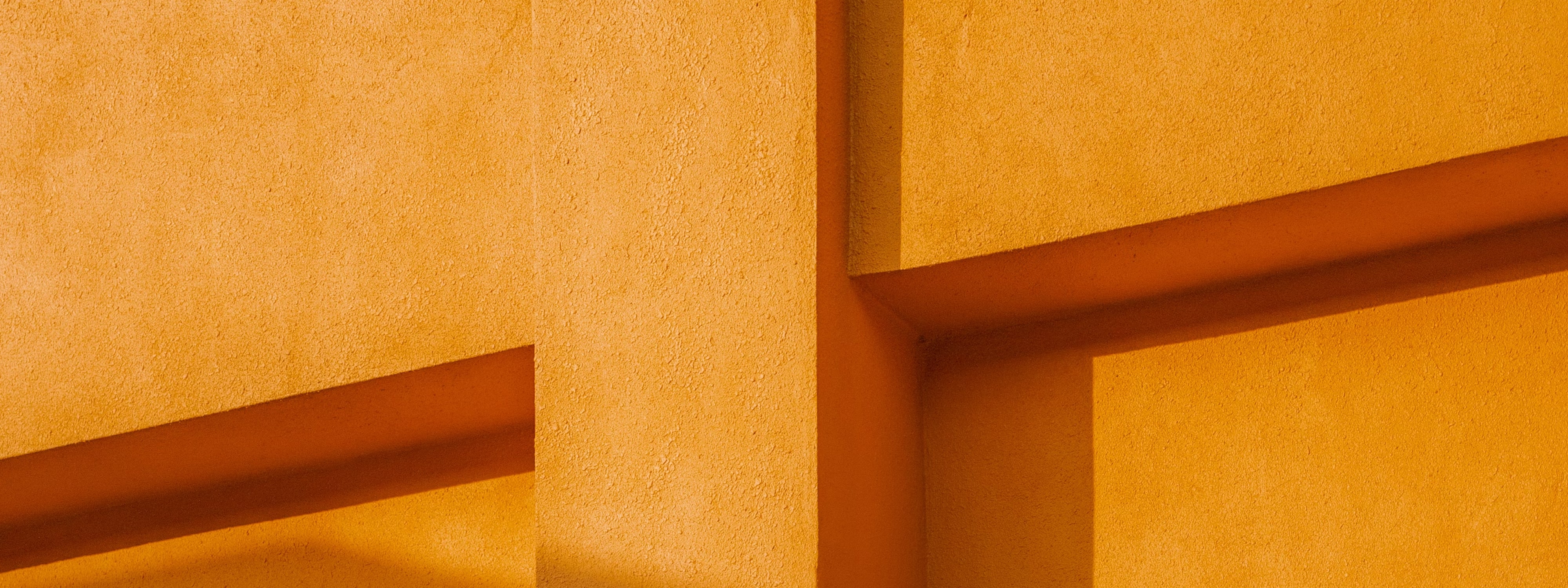 Abstract geometric yellow wall with intersecting shadows and textured surfaces